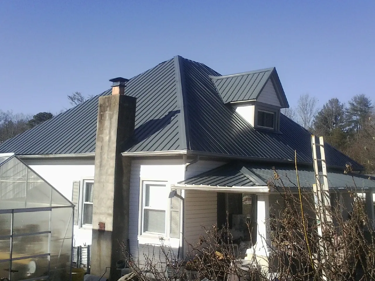 Dark blue standing seam metal roof on a white farmhouse with dormer — Slate & Tile Roof Repair by Roofing Brothers in Port Gamble