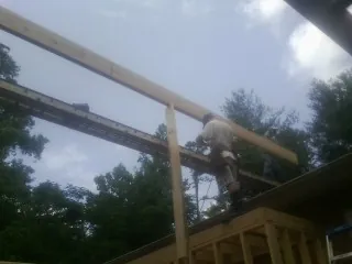 Carpenter setting a ridge beam over a new addition frame — Ice Dam Removal by Roofing Brothers in Port Gamble
