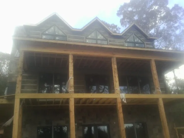 Dormers and porch framing on a large log home under construction — Roof Coating work by our crew in Port Gamble