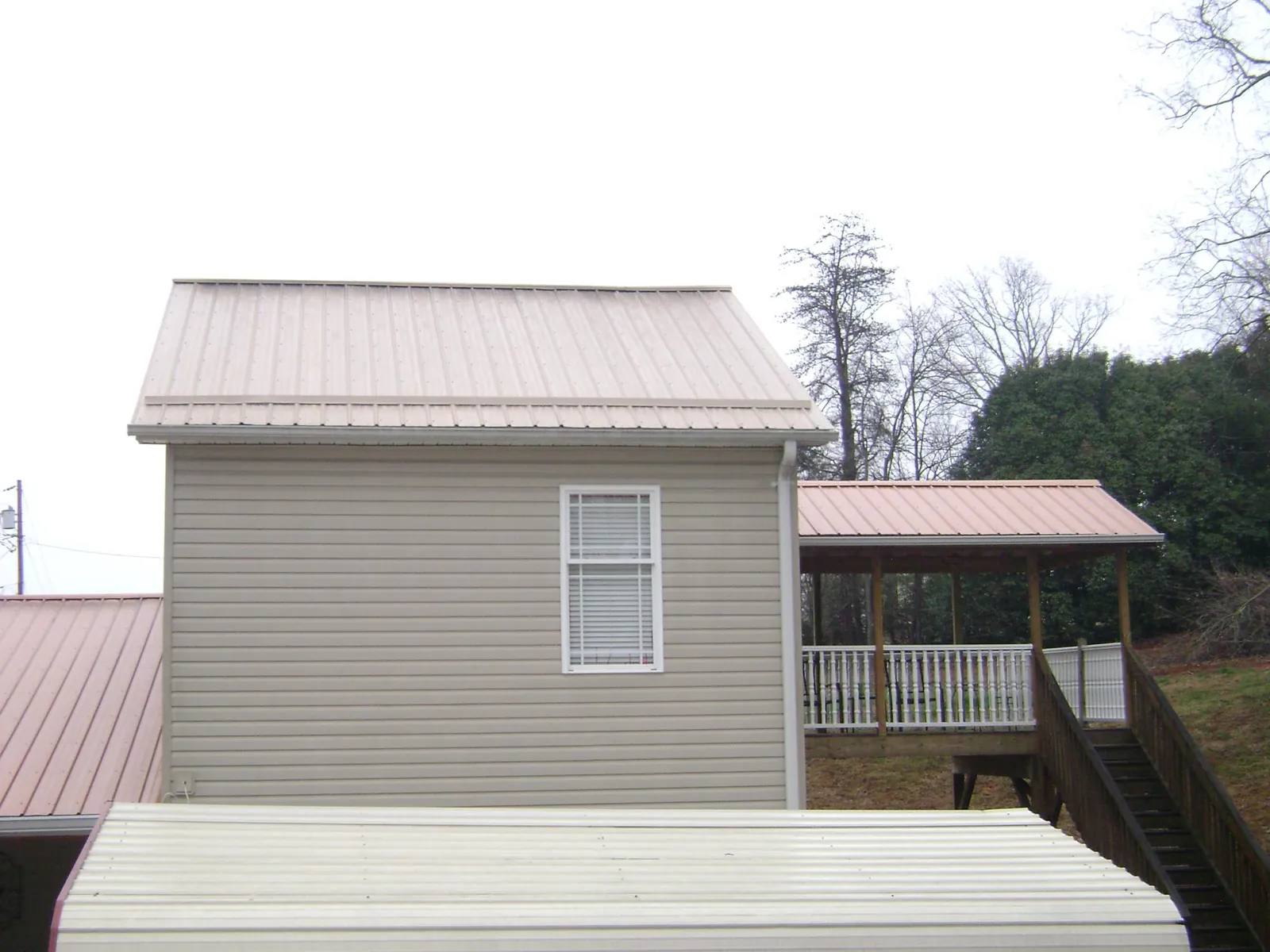 Tan metal roofs on a two story addition and attached porch, from a Roof Replacement job in Port Gamble