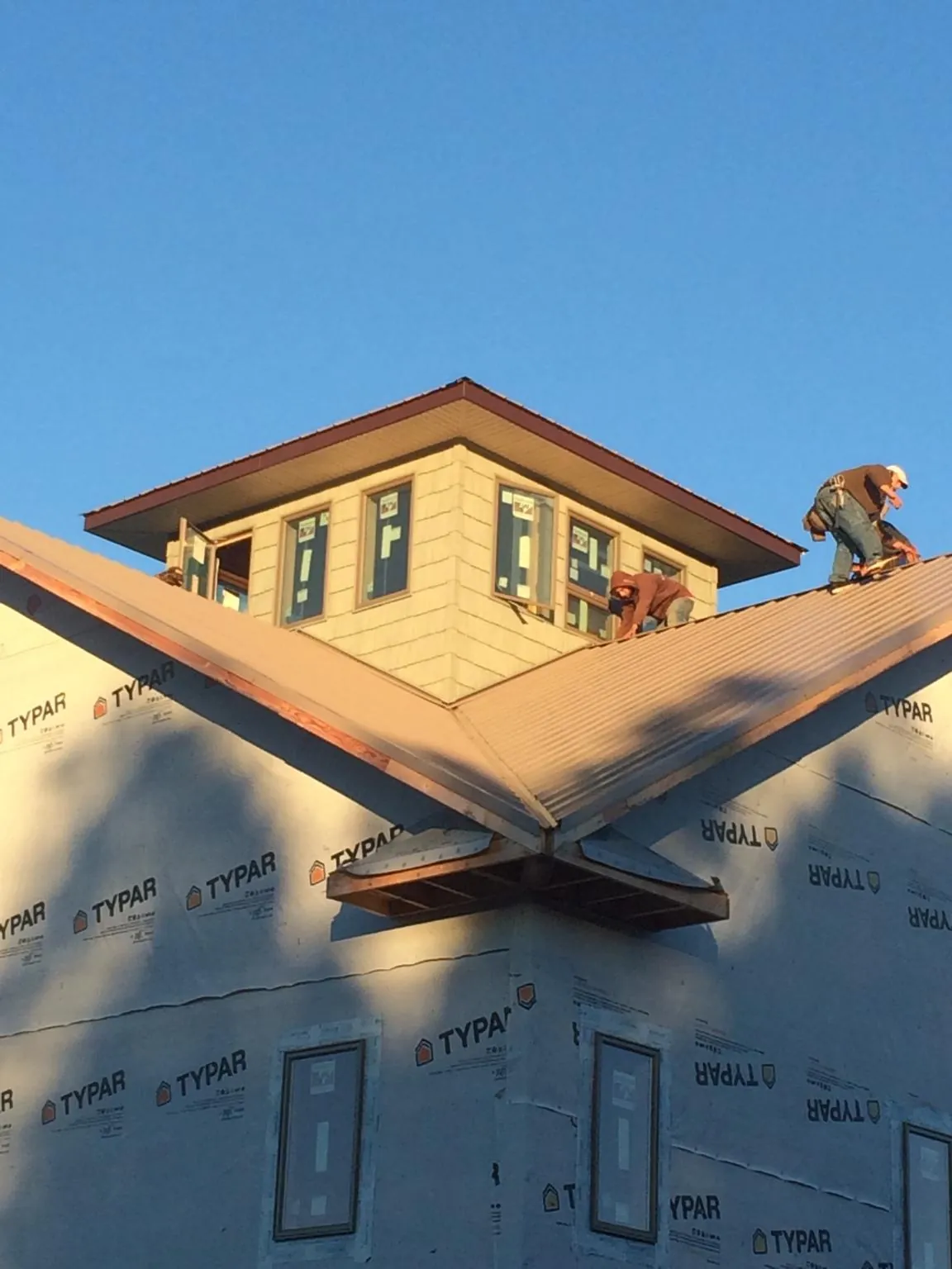 Roofers working around a rooftop cupola on a new metal roof at sunset — Roof Waterproofing in Port Gamble by Roofing Brothers